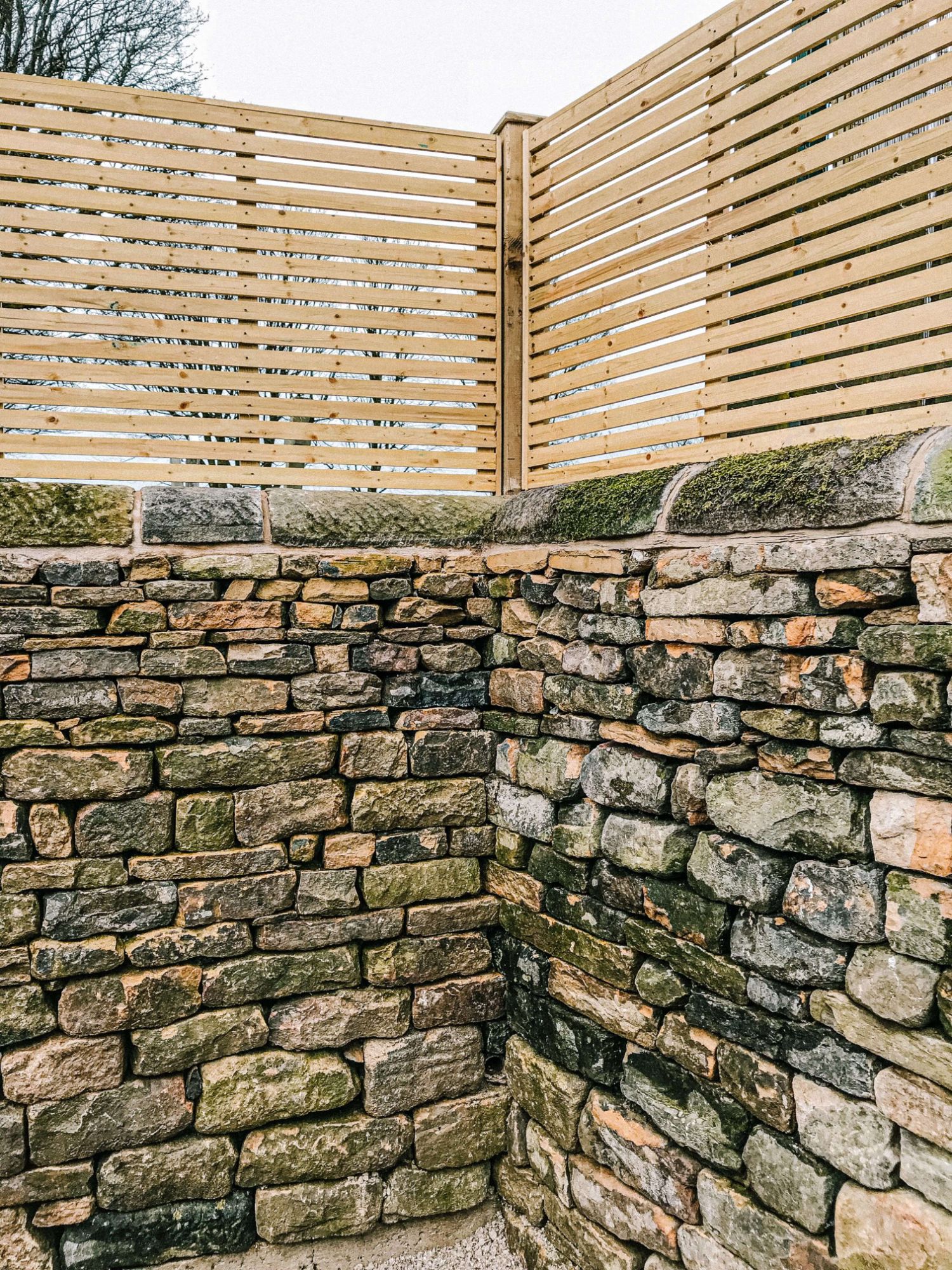 Dry stone walling - A photo of a corner dry stone wall with a fence above created by the Silver Oak team